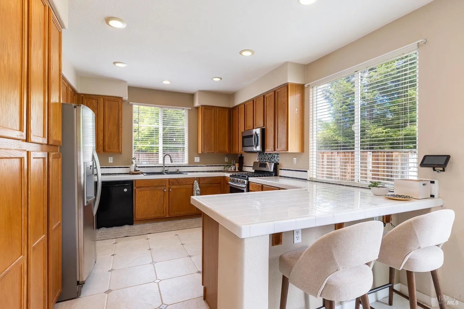 Kitchen with warm wood cabinetry, stainless appliances, and breakfast bar