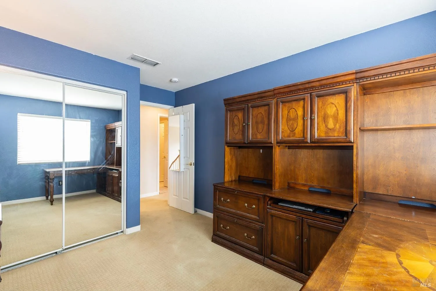 Bedroom office with built-in desk and mirrored closet doors