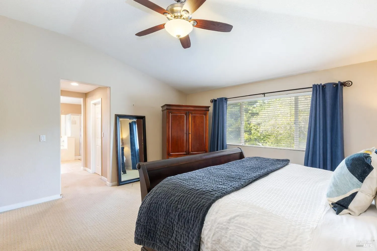 Primary bedroom with vaulted ceiling and en-suite bath beyond