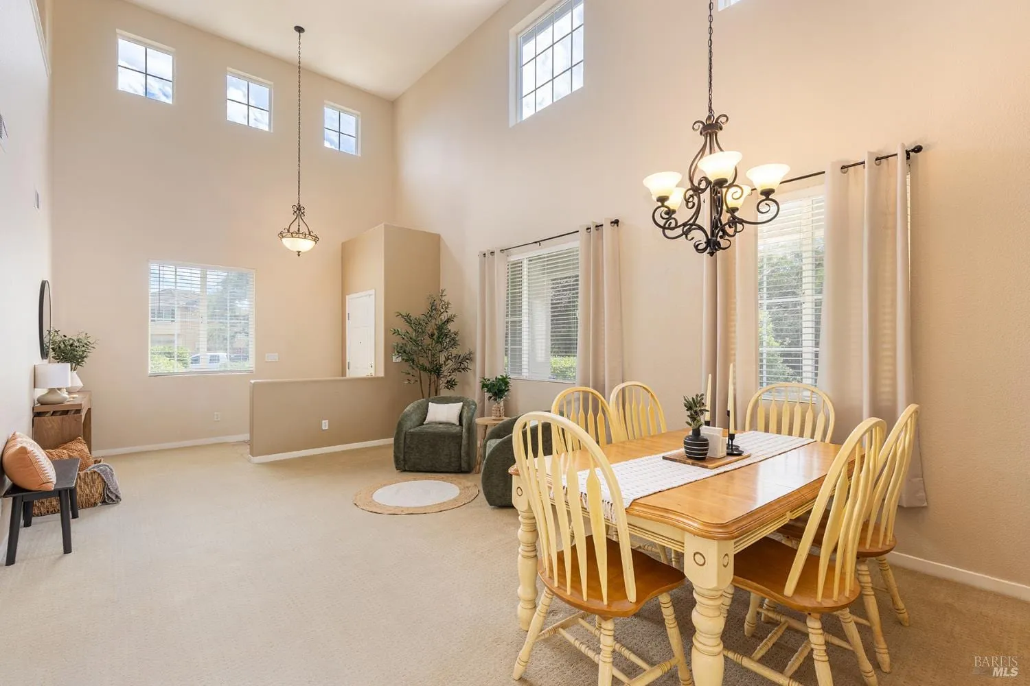 Open dining and living area with vaulted ceilings and chandelier
