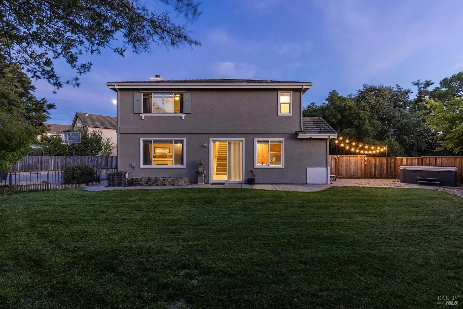 Twilight backyard with string lights, lawn, and patio at Cedar Creek Court